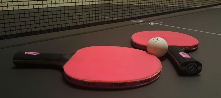 2 rote Tischtennis Schläger auf einer schwarzen Platte